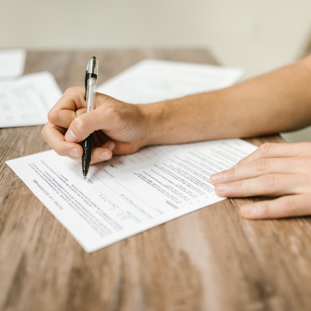 Person filing form with blue pen in hand